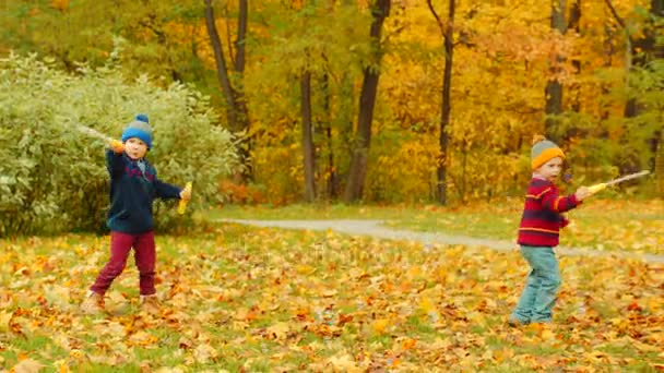 Los niños pequeños están soplando burbujas en el parque de otoño — Vídeos de Stock