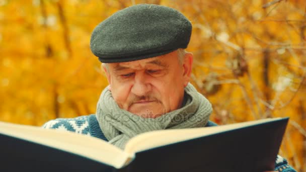 Närbild porträtt av oldman med bok i parken hösten — Stockvideo