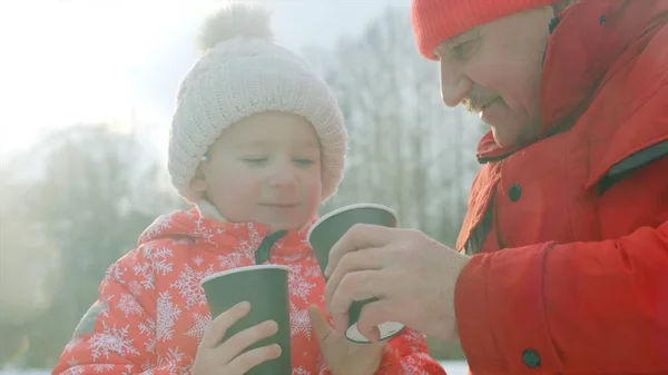 Kleiner Junge und sein Großvater trinken heißen Tee im Winterpark — Stockfoto