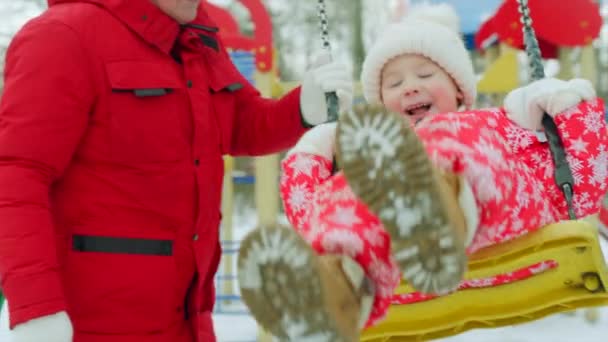 Glücklicher kleiner Junge auf der Schaukel mit seinem Großvater im Winterurlaub — Stockvideo