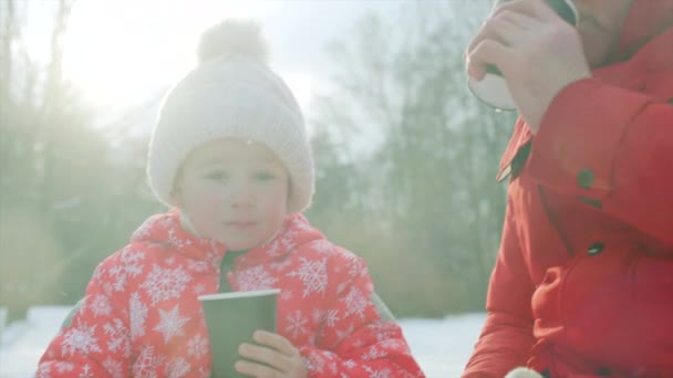 Маленький хлопчик і його дід п'ють гарячий чай після катання на ковзанах на озері — стокове відео