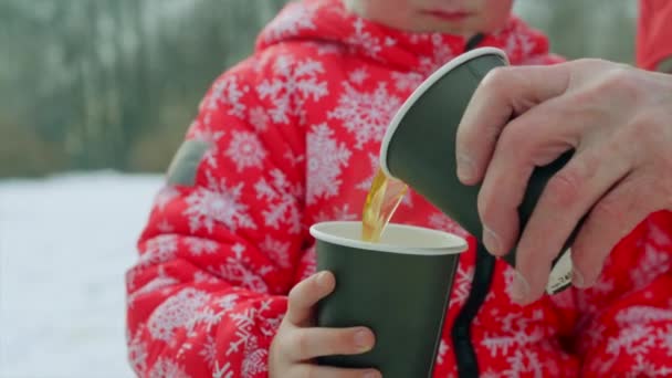 Jongetje en zijn grootvader zijn hete thee drinken na het schaatsen op het meer — Stockvideo