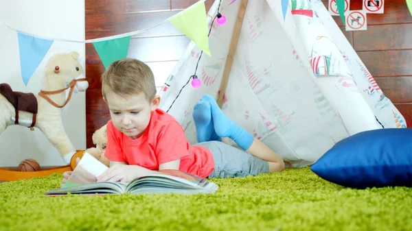 Little boy is reading book in his self made wigwam in playroom — Stock Photo, Image