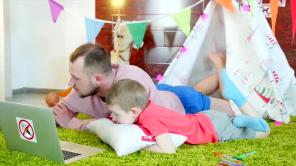 Niño pequeño está viendo dibujos animados con su padre en la sala de juegos — Vídeo de stock