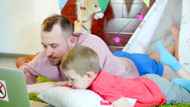 Niño pequeño está viendo dibujos animados con su padre en la sala de juegos — Vídeo de stock