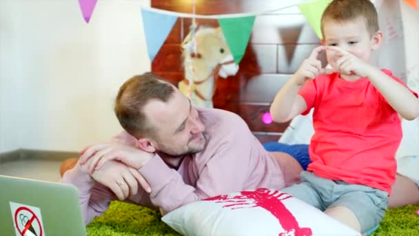 Petit garçon regarde des dessins animés avec son père dans la salle de jeux — Video