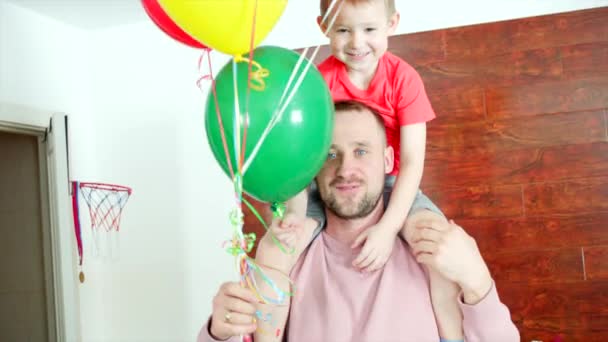 Niño en el cuello de los papás con globos de colores — Vídeos de Stock