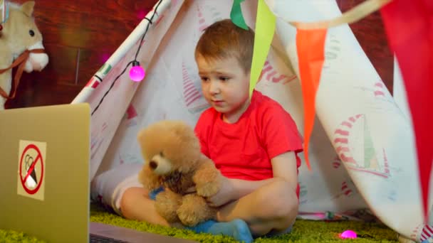 Niño pequeño está viendo dibujos animados en la sala de juegos — Vídeo de stock