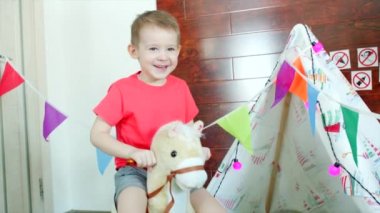 Küçük mutlu çocuk oyun odası oyuncak ata biniyor