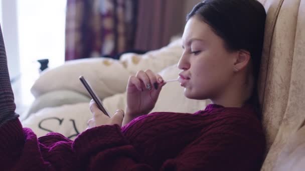 Een Jong Meisje Zuigen Een Lolly Zoek Smartphone — Stockvideo