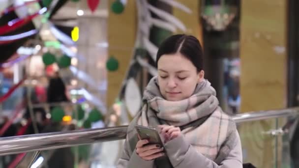 Mädchen schaut auf das Smartphone-Display im Hintergrund des Cafés im Einkaufszentrum. junge attraktive Frau mit Handy in der Hand im Restaurant — Stockvideo