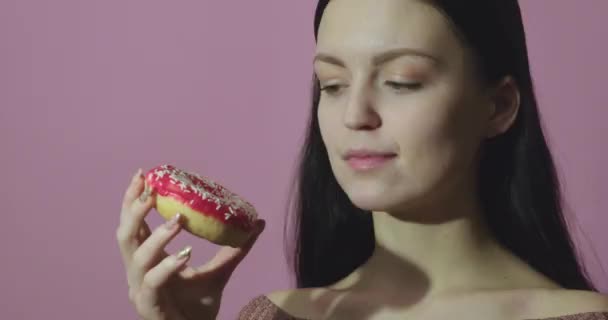 Pembe Arka Planda Izole Edilmiş Donut Yiyen Mutlu Bir Kızın — Stok video