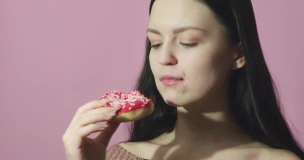 Retrato Cerca Una Chica Guapa Complacida Comiendo Rosquillas Aisladas Sobre — Vídeo de stock