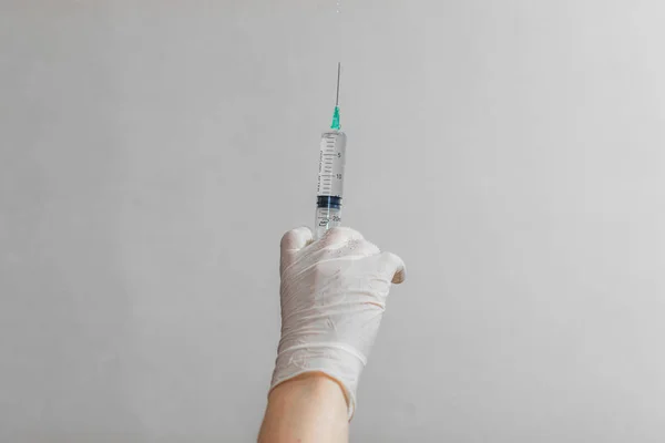 Mão usando luva de látex segurando seringa com um medicamento em fundo branco — Fotografia de Stock