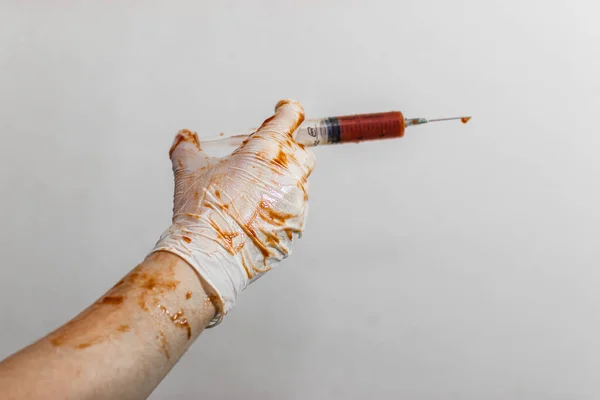 De arts houdt een spuit vast in latex handschoenen, handschoenen in het bloed — Stockfoto