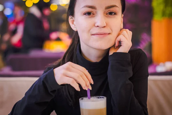 Primer plano retrato de hermosa chica sosteniendo taza de café con leche sentado en la cafetería . — Foto de Stock