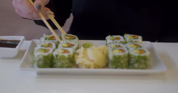 Mujer comiendo sushi en el restaurante, joven hembra sosteniendo palillos y comiendo sushi de salmón en la hora del almuerzo en verano. Estilo de vida de las mujeres comiendo concepto de comida tradicional . — Vídeo de stock