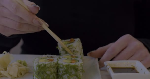 Kvinna äter sushi i restaurang, ung kvinna håller ätpinnar och äter lax sushi i lunchtid på sommaren. Livsstilskvinnor som äter traditionell mat. — Stockvideo