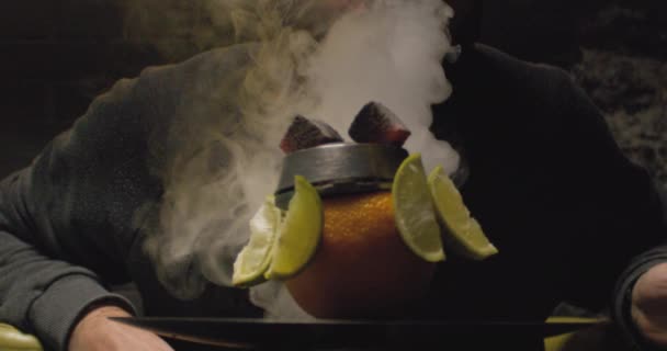 Een man met een baard die een hookah rookt in een donkere kamer. Hookah lifestyle en roken concept. — Stockvideo