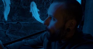 Karanlık bir odada nargile içen sakallı bir adam. Nargile yaşam tarzı ve sigara konsepti. Nargile görünümlü bir denizcinin portresi.