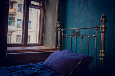 Yatak odasında desenli duvar kağıdı olan ahşap bir yatak. Ahşap zeminde eskimiş botlar ve eski moda bir halı. Antik uyku odası ve iç mekan.