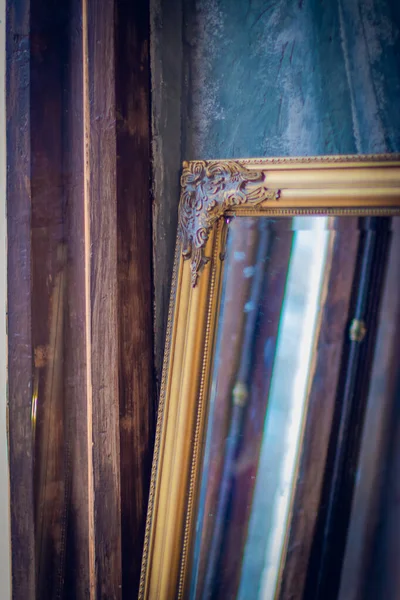 Old antique gold mirror hanging in a vintage room with old pattern wallpaper space for text