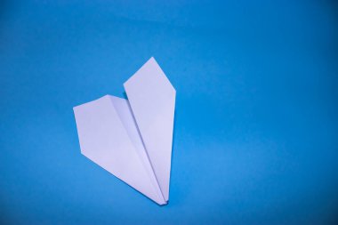 Beyaz kağıt uçağın düz yatağı ve pastel mavi arkaplan üzerine boş kağıt.