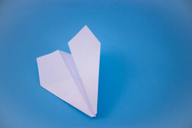 Beyaz kağıt uçağın düz yatağı ve pastel mavi arkaplan üzerine boş kağıt.