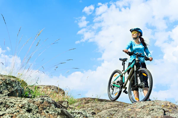 Adult attractive female cyclist  standing on a rock with her mou — Stock Photo, Image
