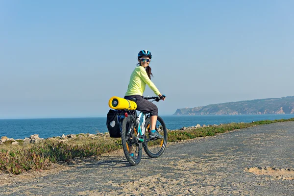 Feliz ciclista turístico de pie en la carretera a lo largo de la orilla del océano — Foto de Stock