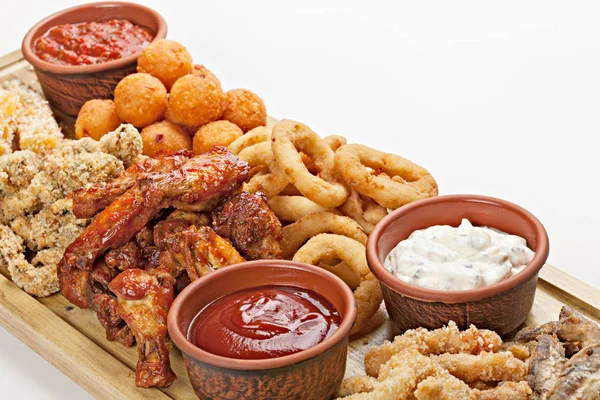 Dish of appetizers to beer. BBQ wings, fried squid rings,  grill