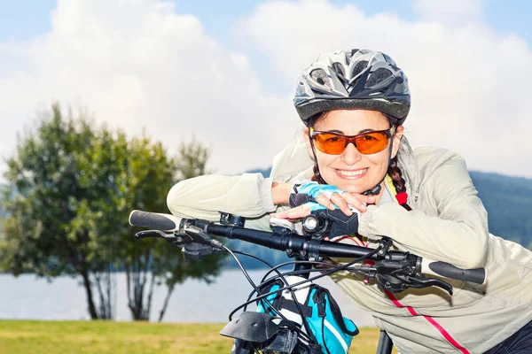 Portrait of mature female tourist cyclist posing on background o — Stock Photo, Image