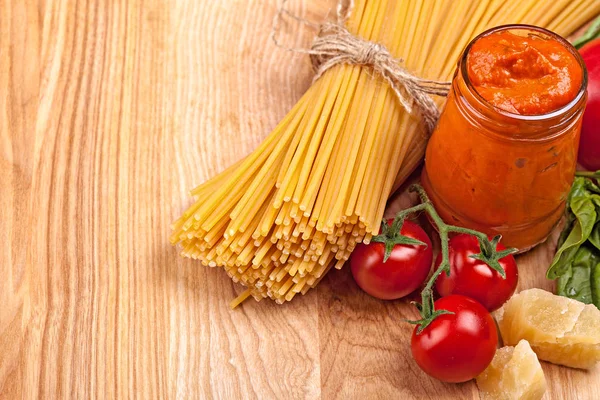 Espaguetis, verduras, trozo de queso y salsa de pesto sobre madera —  Fotos de Stock