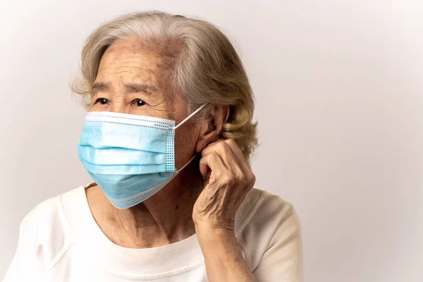 Close-up face of a old Asian woman wearing a mask to prevent Flu epidemic, dust allergy, protection against corona virus(covid-19) , City air pollution