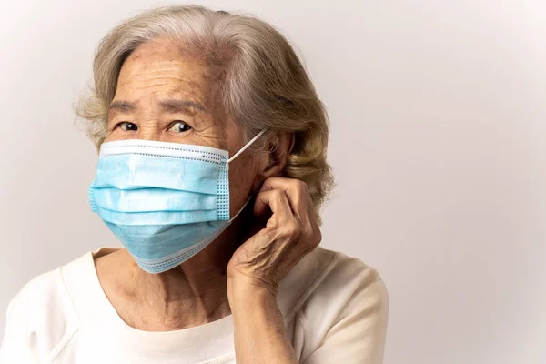 Close-up face of a old Asian woman wearing a mask to prevent Flu epidemic, dust allergy, protection against corona virus(covid-19) , City air pollution