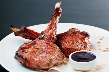 Beyaz bir plaka üzerinde bir sosu ile kavrulmuş domuz eti. Izgara kaburga yakın çekim