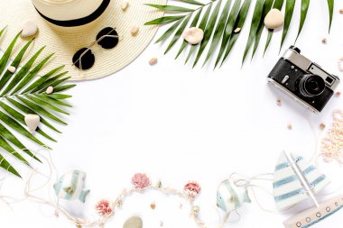 Gezgin aksesuarları, beyaz arka planda tropikal palmiye yaprağı dalları ve metin için boş alan. Seyahat tatili konsepti. Yaz dönemi. Yol iskeleti hazır. Düz yatış, üst görünüm.
