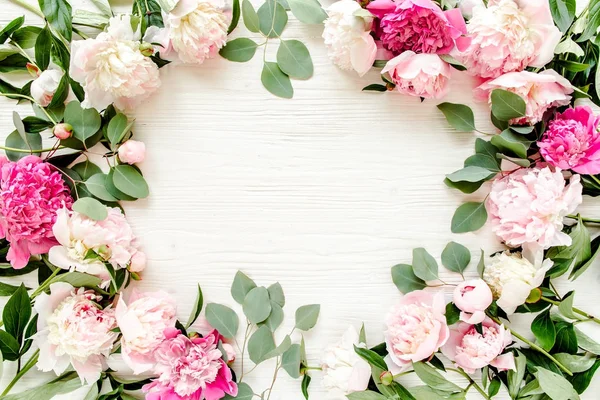 Floral pattern, frame made of beautiful pink peonies on wooden white background. Flat lay, top view. Valentine\'s background. Floral frame. Frame of flowers. Flowers texture