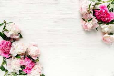Pembe ve kırmızı peonies çiçek tomurcukları dalları ve yaprakları Beyaz ahşap arka plan üzerinde izole kenarlık çerçeve yaptı. Düz yatıyordu, en iyi görünüm. Çerçeve çiçek.