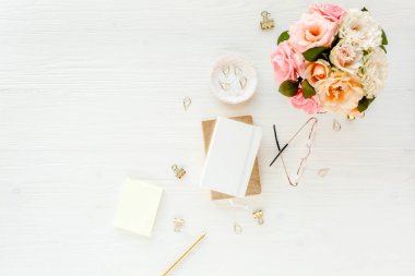 Kadın pembe ve bej gül çiçek buketi, aksesuarlar, günlüğü, beyaz zemin üzerine gözlük ile çalışma alanı. Düz yatıyordu, en iyi görünümü trendy moda kadınsı arka plan. Güzellik blog kavramı.