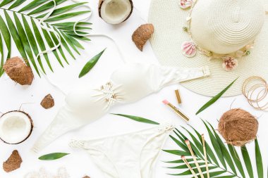 Kadınsı bej mayo plaj aksesuarları, tropikal palmiye yaprağı dal, beyaz zemin üzerine Hindistan cevizi. Yaz arka plan. Yol çerçeve kümesi. Seyahat aksesuarları. Düz yatıyordu, en iyi görünümü. 