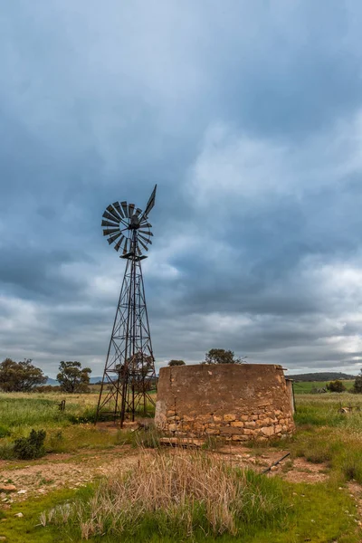Paisagem rural australiana com antiga bomba de água rústica moinho de vento a — Fotografia de Stock