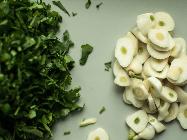 Chopped greens and garlic slices on a cutting board. — Stock Photo, Image