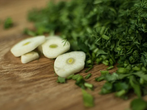 Chopped greens and garlic slices on a cutting board. — Stock Photo, Image