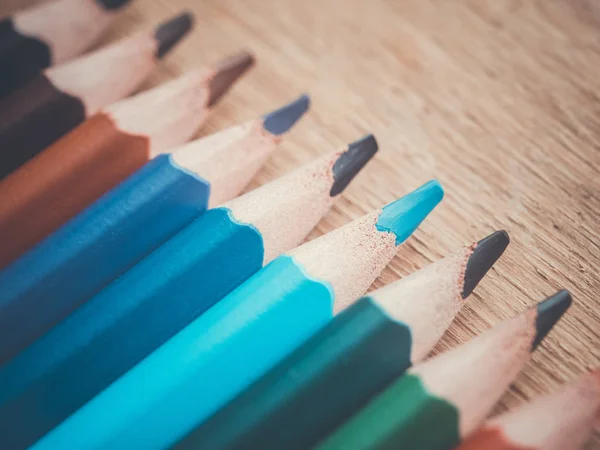 Un conjunto de varios lápices de colores. Lápices en fila sobre una superficie de madera . — Foto de Stock