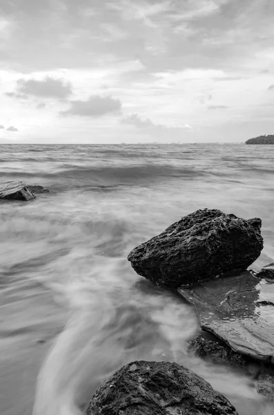 Onda de imagen en blanco y negro golpeando la costa con una nube dramática — Foto de Stock