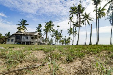 Geleneksel ahşap ev Hindistan cevizi ağacı, yeşil çim ve bulutlu mavi gökyüzü güneşli gün, çevrili bulunan Terengganu, Malezya. 