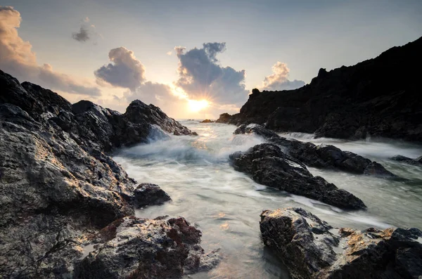 Ondas salpicando sobre a formação de rochas únicas sobre o impressionante fundo do nascer do sol — Fotografia de Stock