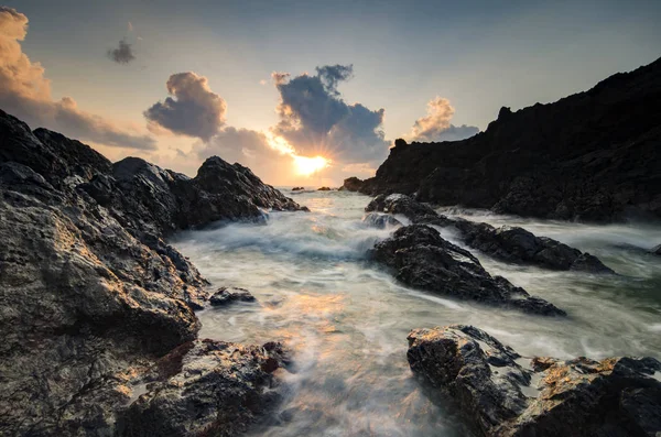 Vlny stříkající na formování jedinečné skály nad pozadím krásný východ slunce — Stock fotografie