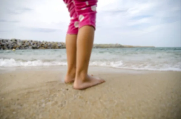 Kleine Mädchen stehen an einem Sandstrand und spielen an sonnigen Tagen mit Wellen — Stockfoto